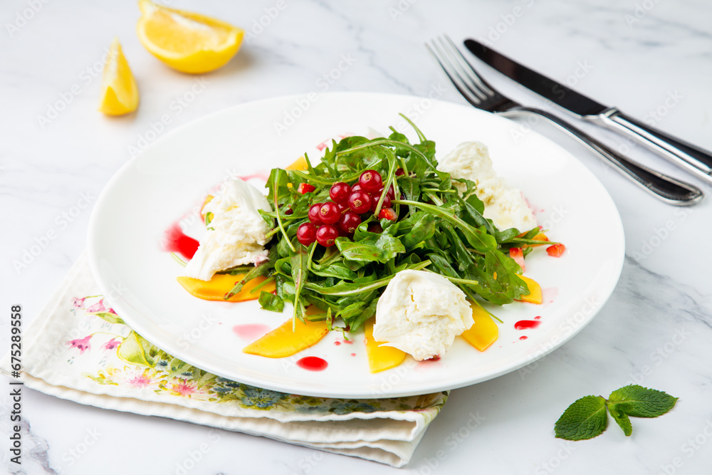 arugula salad with peach slices and red berries on a white plate top view arugula salad with peach slices and red berries on a white plate top view