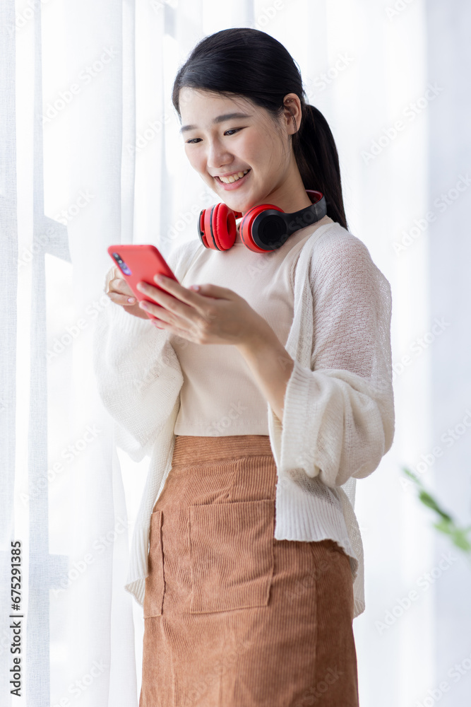 Happy young Asian woman using Phone sitting at desk, studying online, looking at phone screen learning web classes or having virtual call meeting remote working from home. Happy young Asian woman using Phone sitting at desk, studying online, looking at phone screen learning web classes or having virtual call meeting remote working from home.