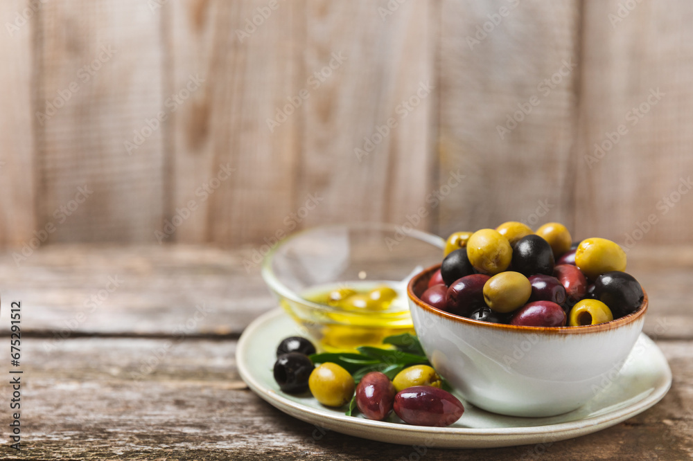 Green, black and red olives, olive oil on a brown wooden background. Fresh juicy olives in a bowl and fresh olive leaves. Vegan. Olive fruits. Place for text. Copy space. Green, black and red olives, olive oil on a brown wooden background. Fresh juicy olives in a bowl and fresh olive leaves. Vegan. Olive fruits. Place for text. Copy space.
