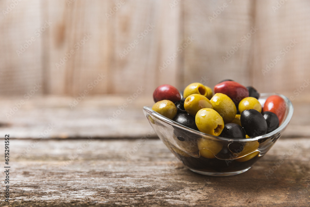 Green, black and red olives, olive oil on a brown wooden background. Fresh juicy olives in a bowl and fresh olive leaves. Vegan. Olive fruits. Place for text. Copy space. Green, black and red olives, olive oil on a brown wooden background. Fresh juicy olives in a bowl and fresh olive leaves. Vegan. Olive fruits. Place for text. Copy space.