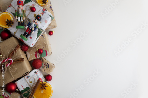 Wrapped gifts and Christmas tree decorations with candies laid out on a white background copy space