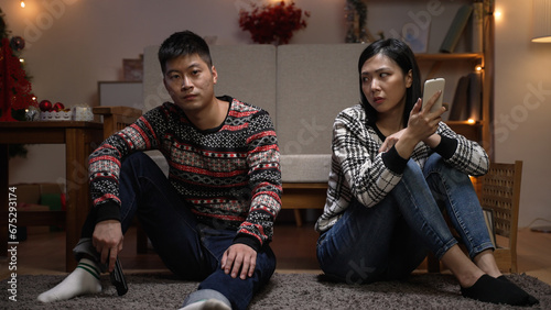 Foto unhappy asian married couple pushing each other while they are sitting on the gr