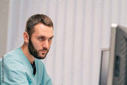 A smiling and concentrated radiologist sits at his desk and diagnoses patients on magnetic resonance imaging machine