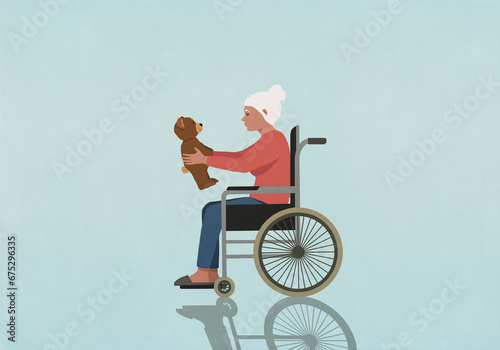 Senior woman in wheelchair holding teddy bear on blue background
 photo