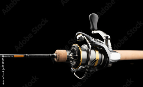 Fishing rod spinning with the line close-up. Fishing rod and reel isolated on black background. Fishing rod rings. Tackle. Fishing spinning reel. photo