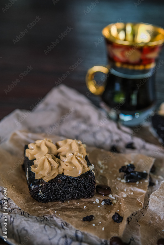 Cup of coffee with chocolate brownies with cream and coffee beans on rustic recipe papers Cup of coffee with chocolate brownies with cream and coffee beans on rustic recipe papers