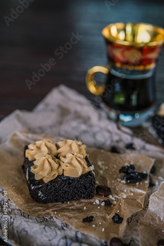 Cup of coffee with chocolate brownies with cream and coffee beans on rustic recipe papers