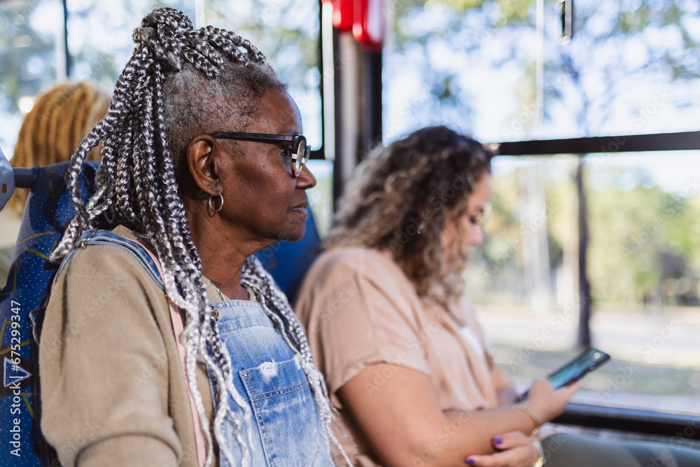 Mulher negra senior com penteado afro sentada no onibus.