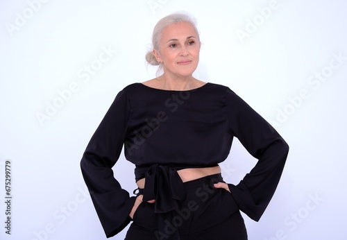 Aged mature woman in black suit on white background with smooth healthy skin face. Beautiful aging mature woman with blonde hair and happy smiling touching face. 