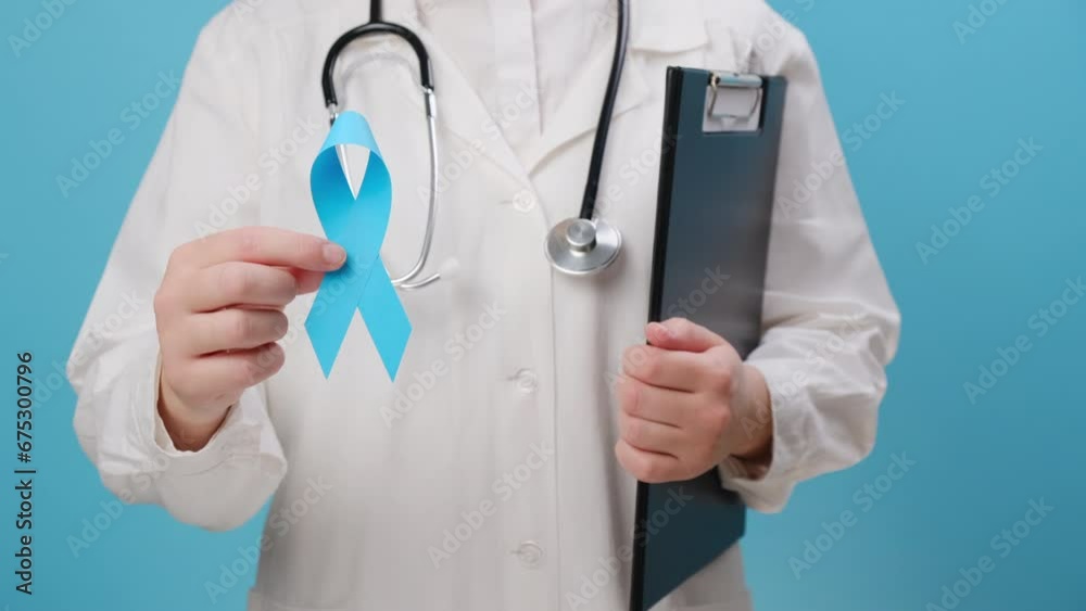 Close up of unrecognizable woman doctor in white uniform with stethoscope holding blue ribbon awareness. Men's health and Prostate cancer awareness campaign in November month. Symbol of medical issues Close up of unrecognizable woman doctor in white uniform with stethoscope holding blue ribbon awareness. Men's health and Prostate cancer awareness campaign in November month. Symbol of medical issues