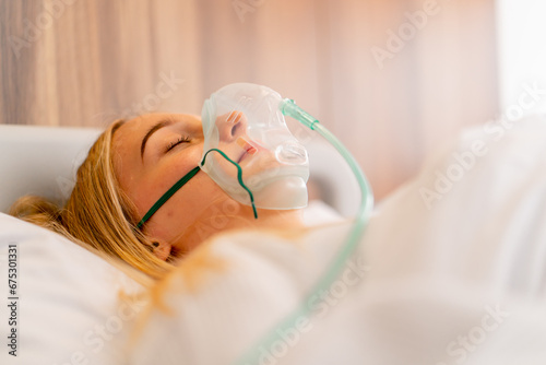 Close-up shot of a young girl lying in intensive care in an oxygen mask in hospital to maintain the health and life of the patient photo