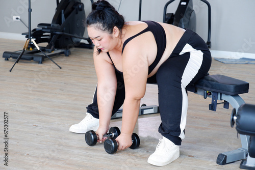 Young Asian woman lifting dumbbells exercising in the gym. exercise concept.