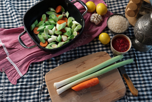 turkish-style braised leeks food cooken in olive oil, fresh vegetables cut process with all ingredients on kitchen textile background, authentic look