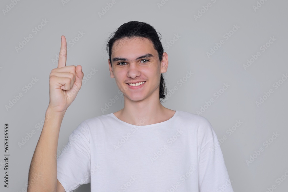 Young man, teenager shows index finger up and smiles Young man, teenager shows index finger up and smiles