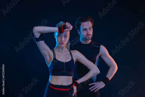 Gym and fitness concept. Strong athletic woman and man on black background wearing in the sportswear.