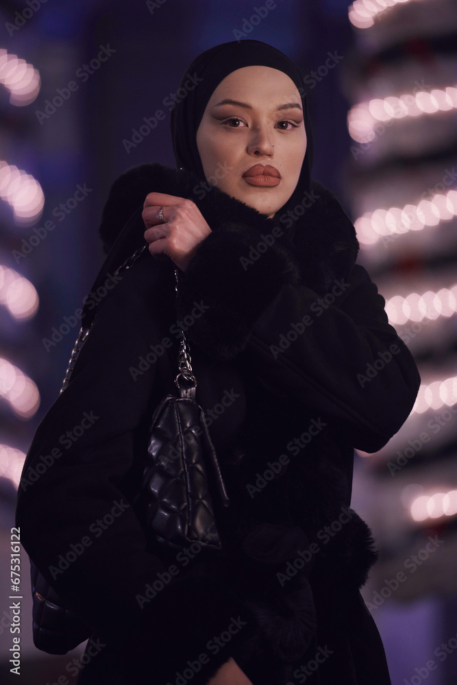 Muslim woman walking on an urban city street on a cold winter night wearing hijab Muslim woman walking on an urban city street on a cold winter night wearing hijab