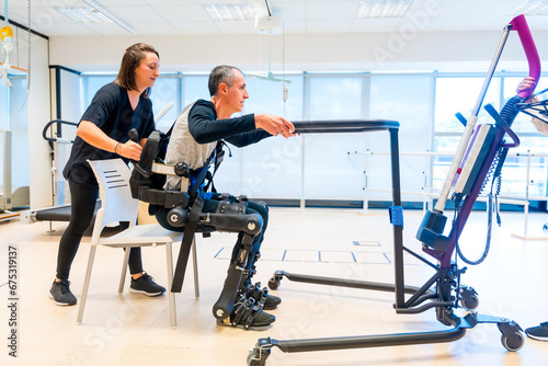 Mechanical exoskeleton. Physiotherapy assistant lifting disabled person with robotic skeleton to get up. Futuristic rehabilitation, Physiotherapy in a modern hospital