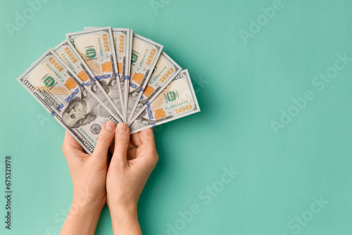 Dollars in hands on green background top view copy space