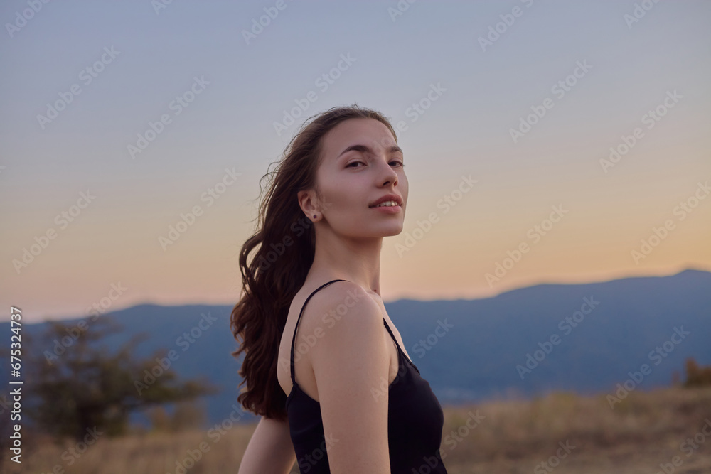 a beautiful woman poses against the backdrop of a sunset in the mountains, enjoying the view