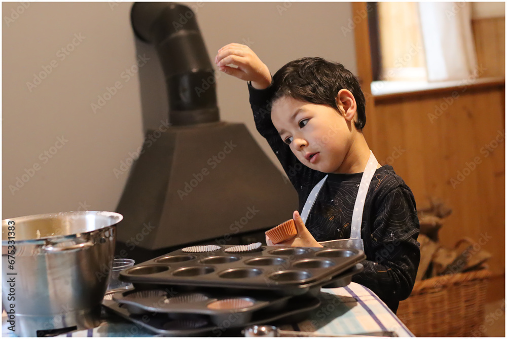 Baking concept Child play messy fancy cup cake muffin. Boy hand holding scoop putting cake batter in a tin cases. Baking concept Child play messy fancy cup cake muffin. Boy hand holding scoop putting cake batter in a tin cases.