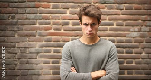 Hombre joven enfadado con los brazos cruzados fondo de pared o muro de ladrillos