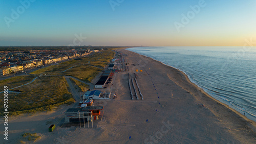 Beautiful flight in summer over the beach in Katwijk aan Zee. People are resting near the sea. Houses for tourists. Beach umbrellas, rides, people swimming in the sea. Beach in Netherland. North Sea. photo