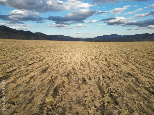 Barren landscape featuring a dirt-covered terrain, with distant mountains in the background.