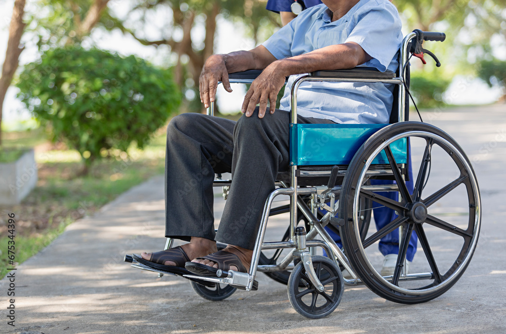 Cropped image of elderly man sits in a wheelchair outdoors in nature. Cropped image of elderly man sits in a wheelchair outdoors in nature.