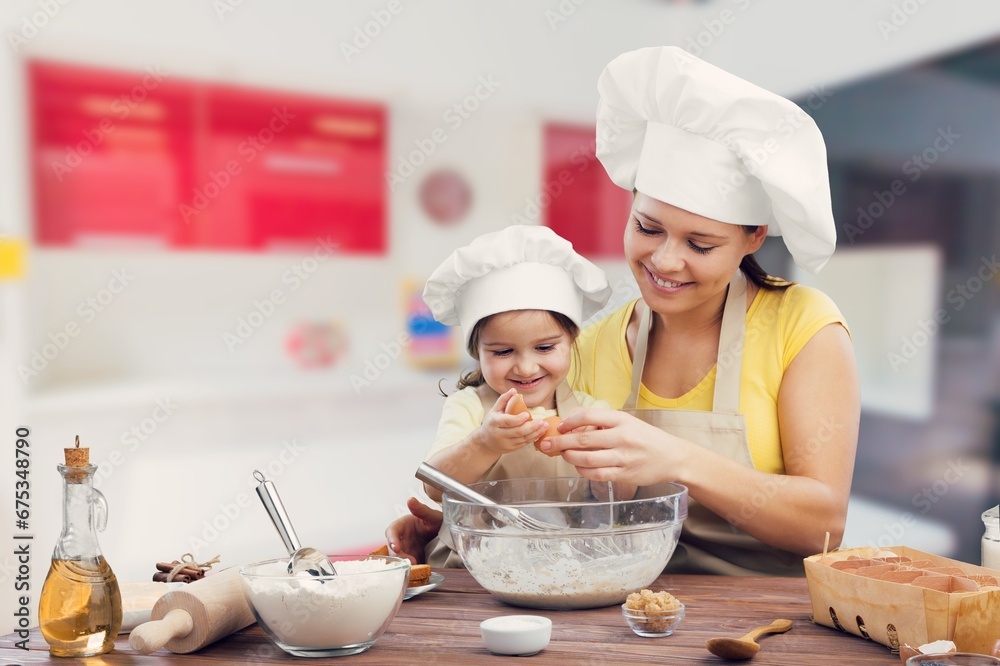 Happy young mother and daughter preparing a homemade dish Happy young mother and daughter preparing a homemade dish