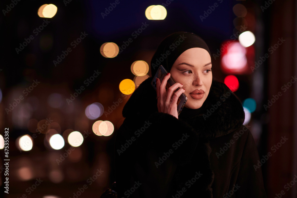 uropean Muslim Hijabi Business Lady checking her phone on urban city street at night uropean Muslim Hijabi Business Lady checking her phone on urban city street at night