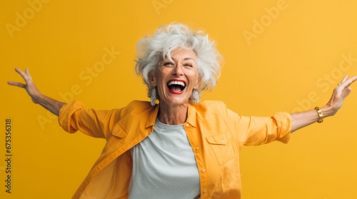 Happy senior woman in colorful yellow outfit, cool dancing laughing and having fun in fashion studio
