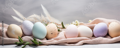 Composition with beautiful pastel colored Easter eggs, spring plant leaves and cloth on grey background photo