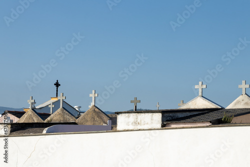 row of different sized and styled stone crosses on top of a white wall against a clear blue sky, ai generative