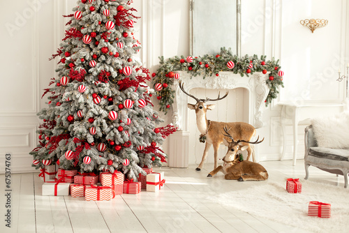 Stylish white living room interior with decorated Christmas tree, fireplace and sofa with pillows. Christmas at home. New year winter home decor. Xmas tree with lights glowing garlands and gifts	
