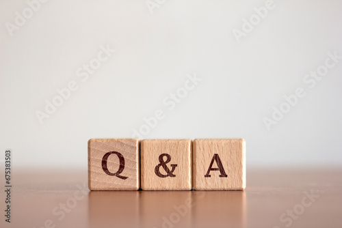 Questions and answers Q&A text on a background of wooden blocks placed on a blurred background table. Business and communication concepts
