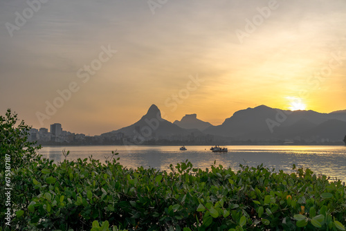 Evening at Rodrigo de Freitas lagoon with pedal boats and sunset behind the mountains. In the background, the buildings of Ipanema, Morro Dois Irmãos and Pedra da Gávea. photo