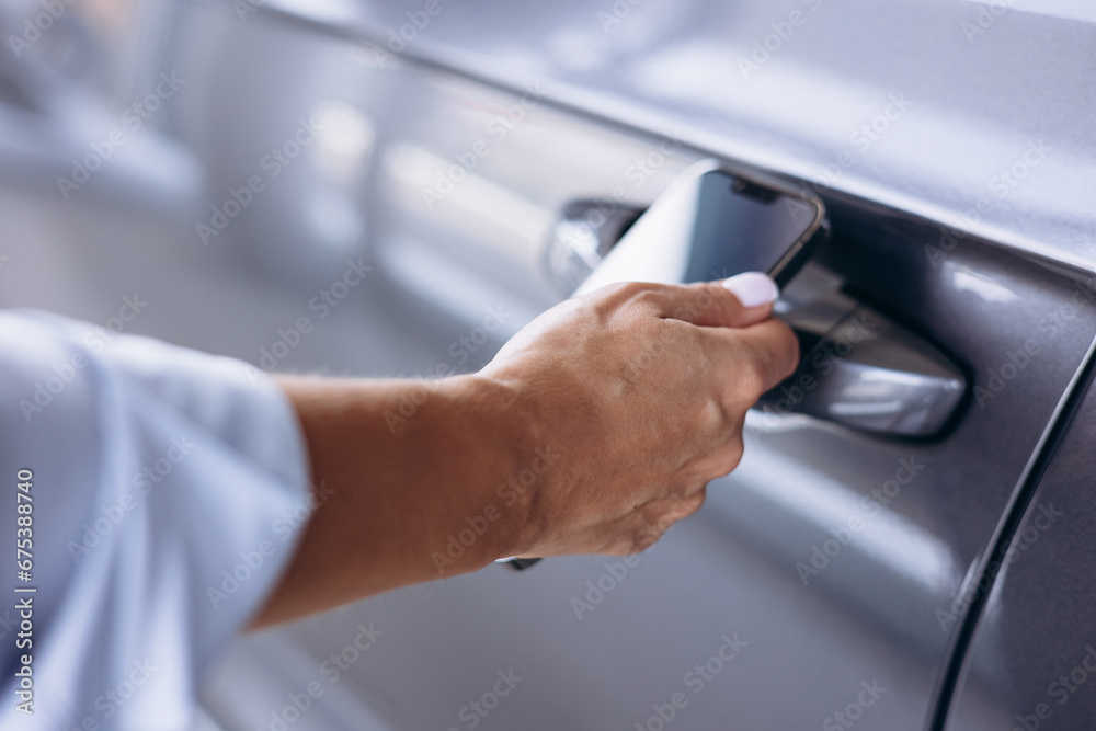 Woman using mobile phone to open her car Woman using mobile phone to open her car