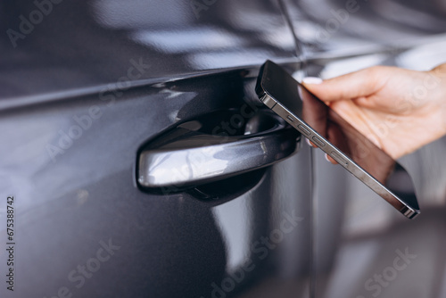 Woman using mobile phone to open her car