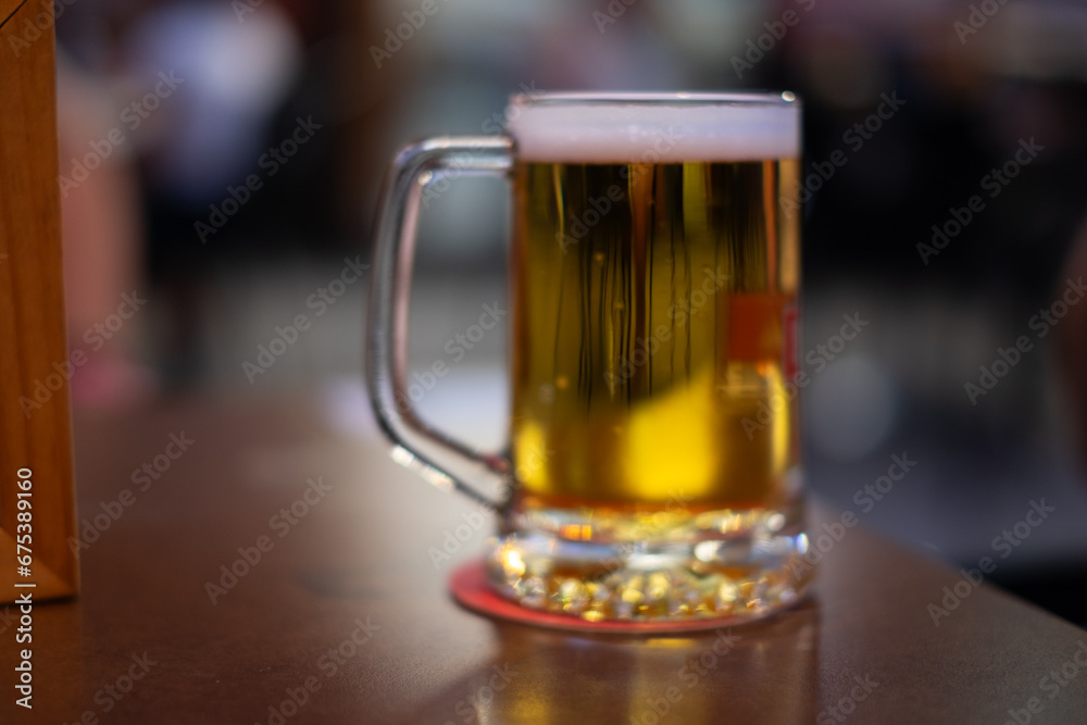 Defocused pint of cold blond beer on pub table. Alcoholic iced beverage