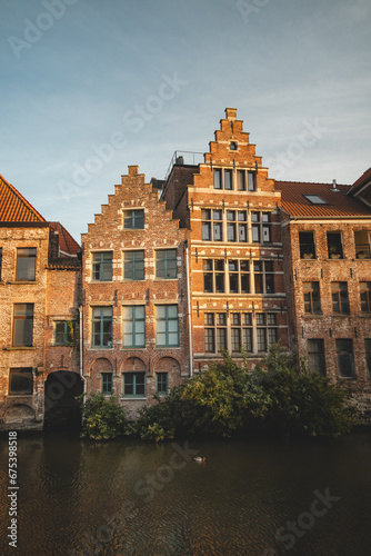 Last remnants of the evening sun illuminate historic buildings on the waterfront in downtown Ghent, Belgium