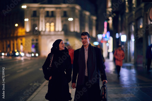 Happy multicultural business couple walking together outdoors in an urban city street at night near a jewelry shopping store window.