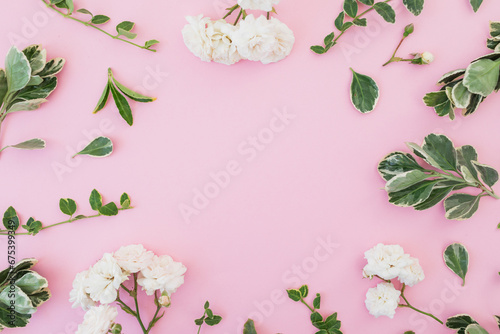 Roses flowers and green leaves on pink background. Flat lay, Top view photo