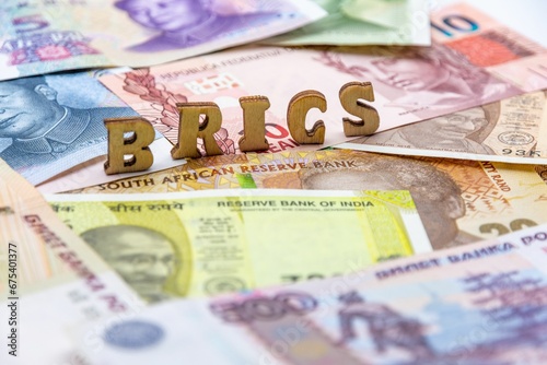 Closeup of a stack of various currency banknotes with the letters BRICS on top photo
