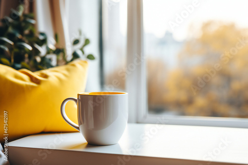breakfast with coffee in bed. Yellow coffee mug, cozy yellow blanket at a sofa in a living room with big bright window. Home modern interior. 
