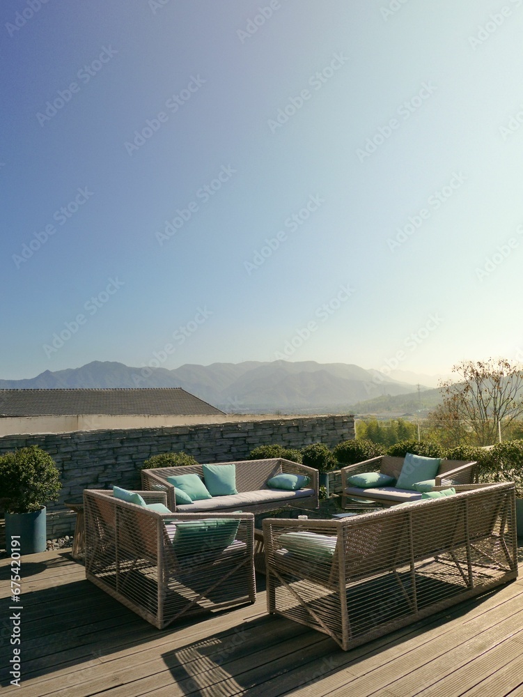 Fototapeta premium Cozy outdoor patio setup with a wooden table and chairs set against a classic stone wall