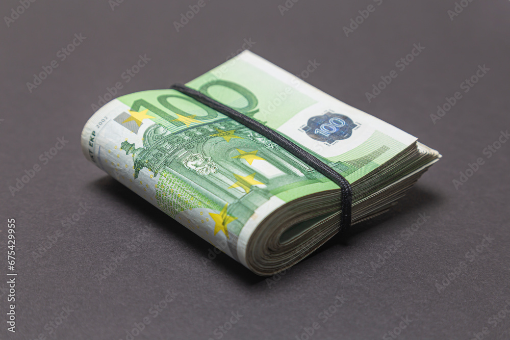 A bundle of 100 EURO banknotes folded in half on a dark background.
A bundle of 100 EURO banknotes folded in half on a dark background.
