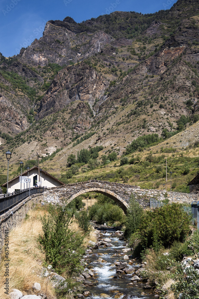 Medieval stone bridge over the river in Espot village in Pyrenees mountains, summer