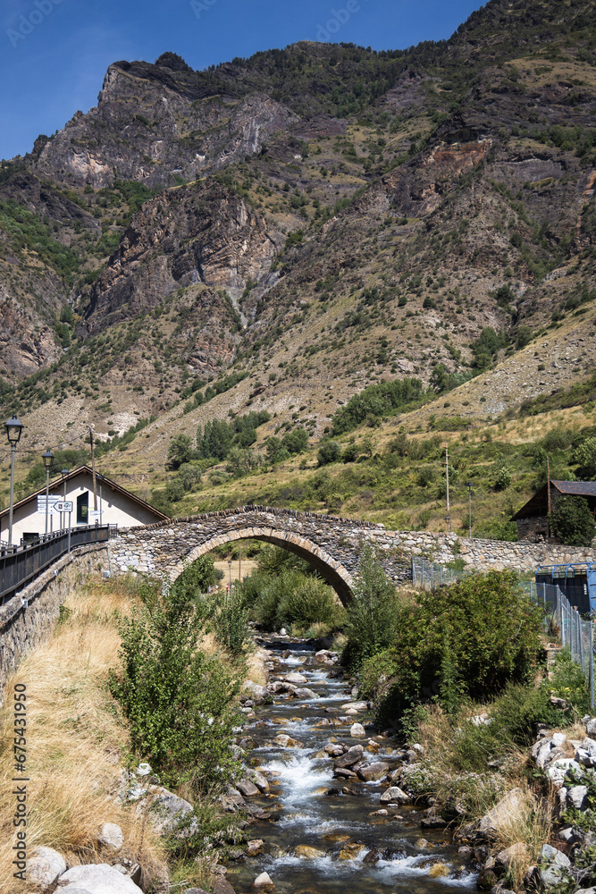 Medieval stone bridge over the river in Espot village in Pyrenees mountains, summer