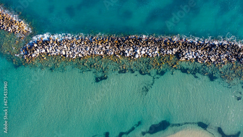 Horizontal aerial view of a narrow rocky island in the green beautiful ocean