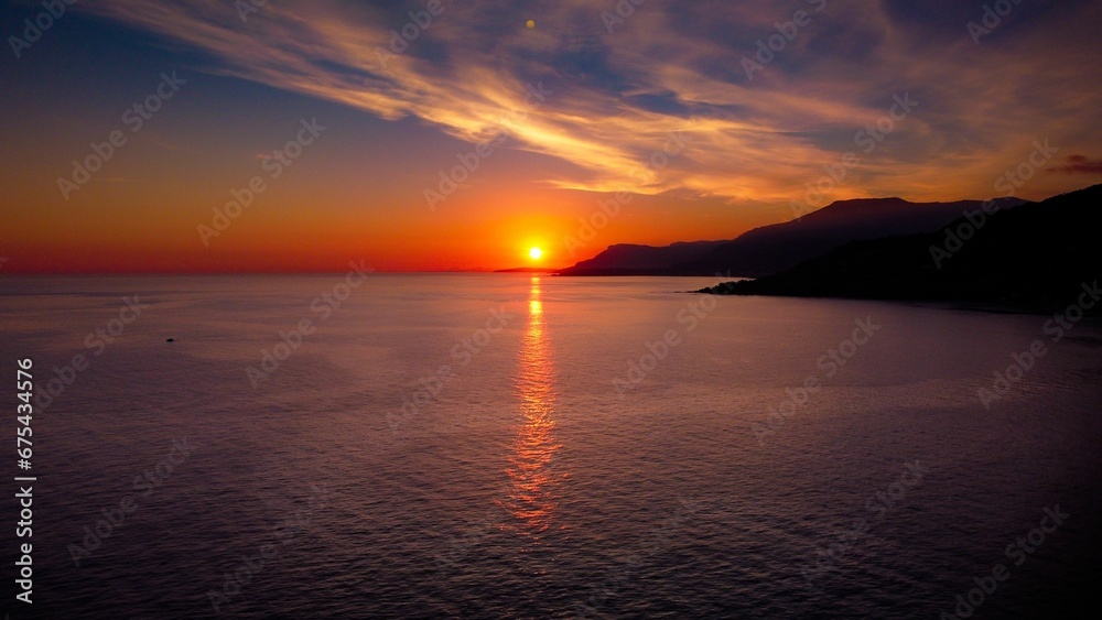 the sun setting over the ocean in front of mountains